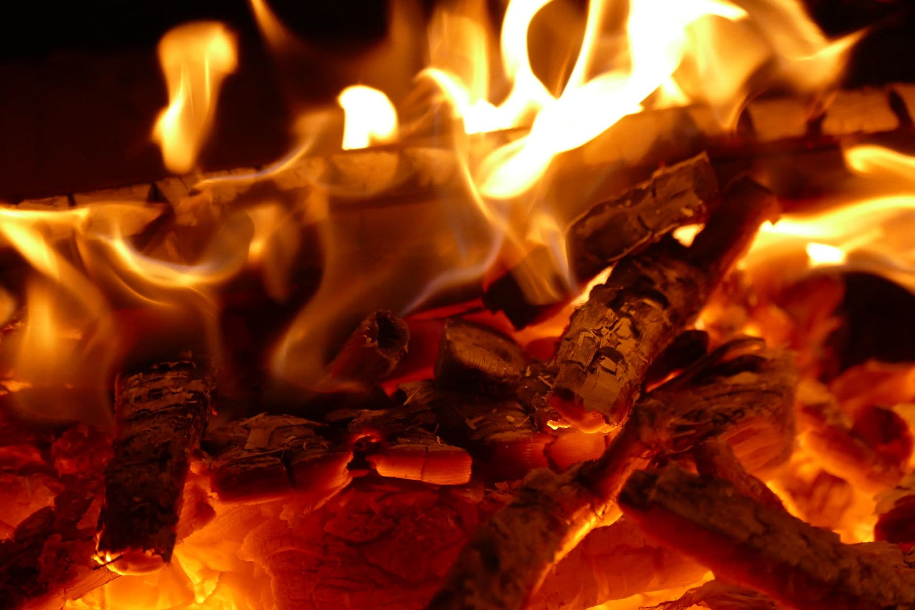 A warm and detailed shot of a campfire with glowing embers, showcasing vibrant flames and wood.